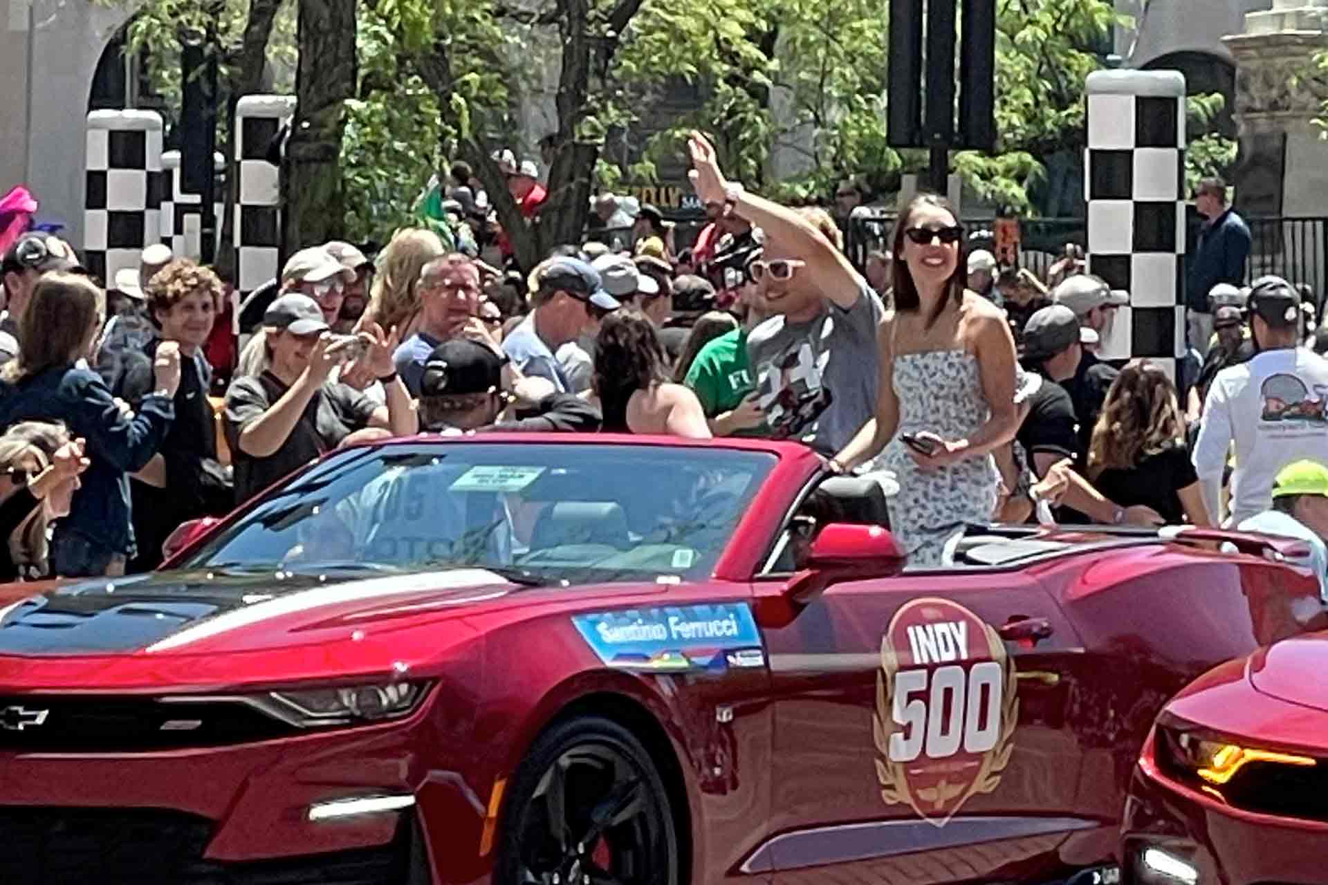 Ferrucci waving to the crowd from a red car at IndyCar events.